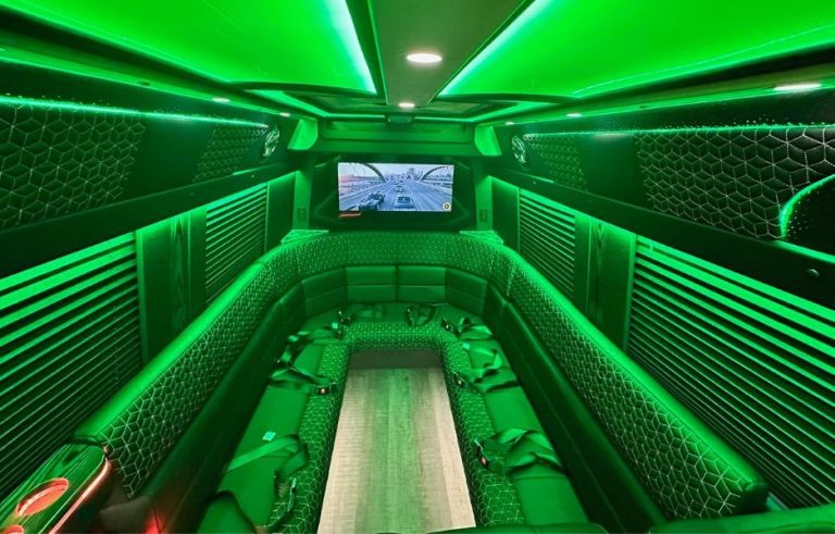 Spacious party bus interior featuring green LED lighting, quilted leather bench seating, and flat-screen TV