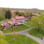 Aerial view of rustic red barn wedding venue surrounded by spring foliage and winding driveways
