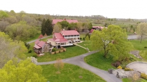 Aerial view of rustic red barn wedding venue surrounded by spring foliage and winding driveways