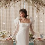 Bride in modern wedding dress with dramatic ruffled shoulders and sheer sleeves at elegant candlelit reception