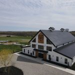 Aerial view of Seven Willows white barn-style wedding venue with metal roof and surrounding farmland