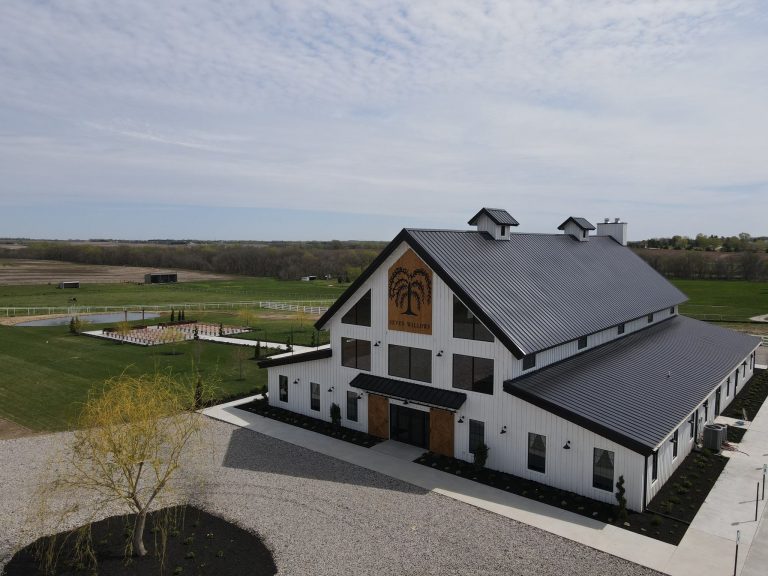 Aerial view of Seven Willows white barn-style wedding venue with metal roof and surrounding farmland