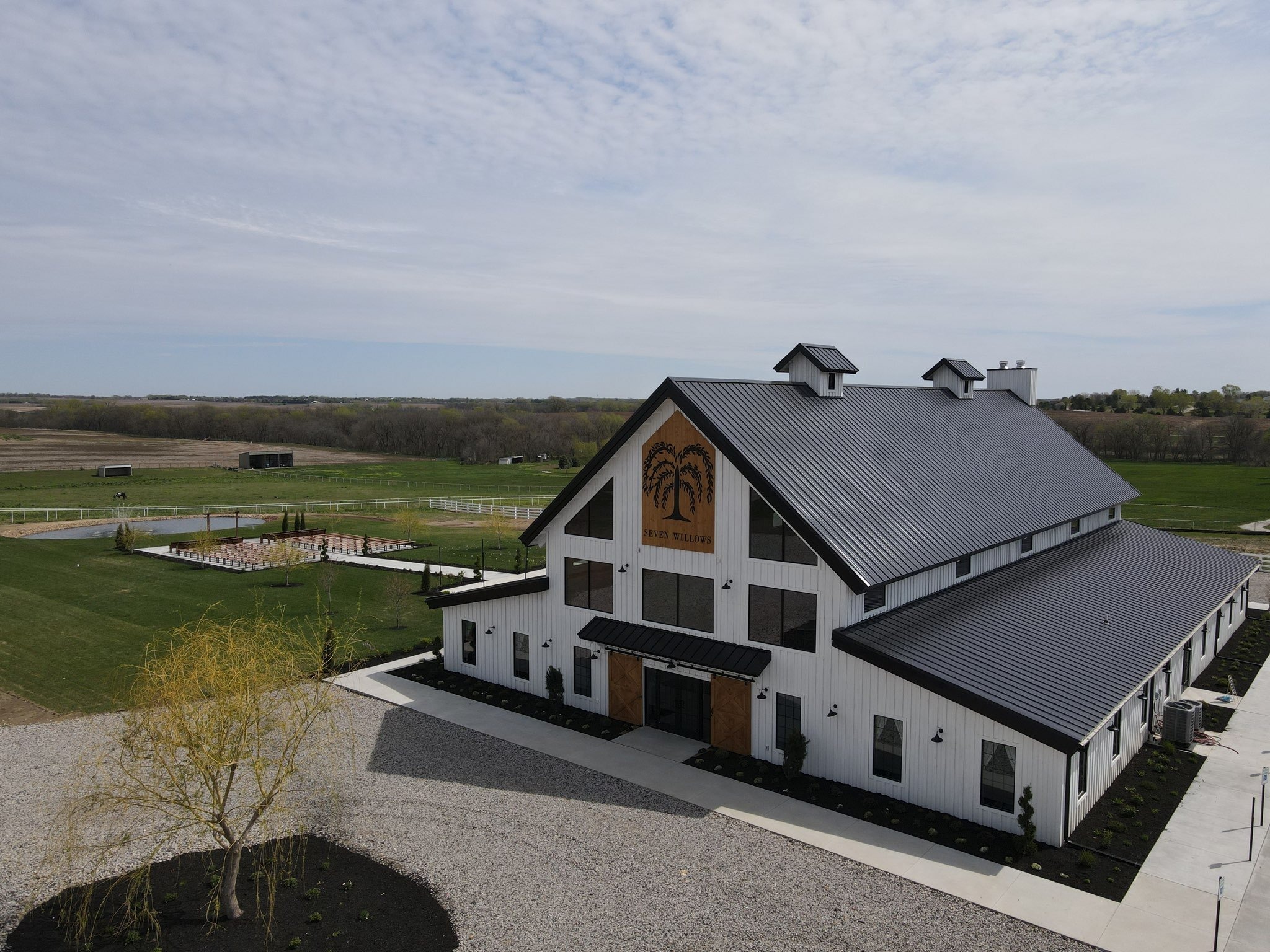 Aerial view of Seven Willows white barn-style wedding venue with metal roof and surrounding farmland