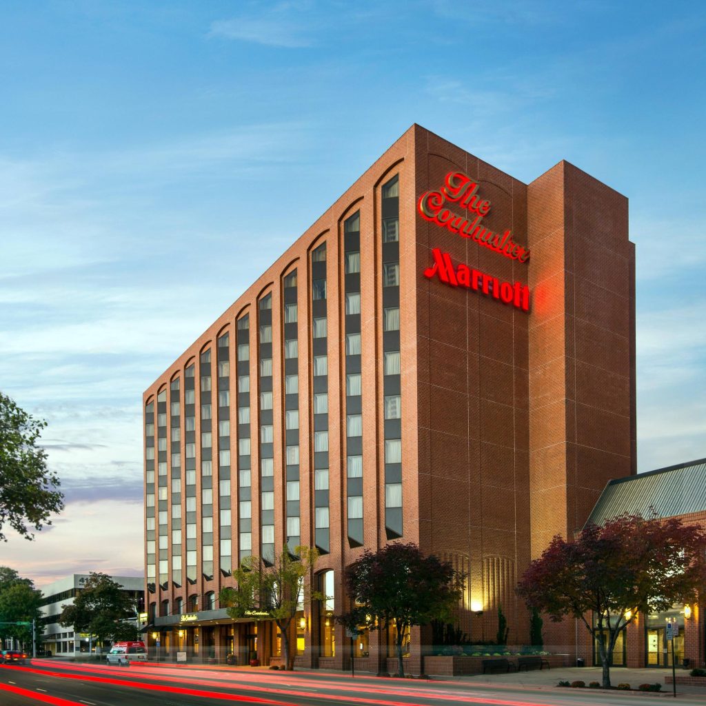 The Cornhusker Marriott hotel exterior at dusk, a tall brick building with illuminated red signage