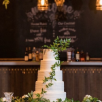 Five-tier white wedding cake with horizontal texture and cascading greenery garland