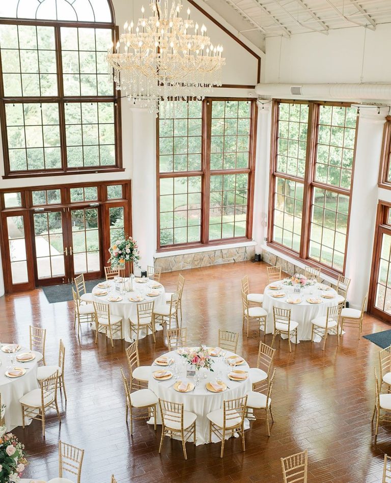 Overhead view of elegant wedding reception hall with round tables, white chairs, and large windows