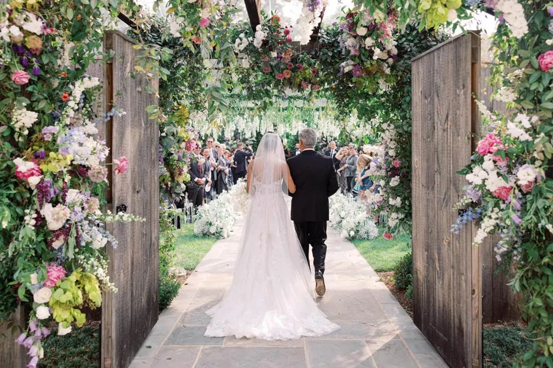 Dad and daughter walking down wedding aisle in garden outdoor setting