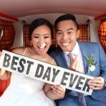 Newlyweds inside vintage van holding "BEST DAY EVER" sign and smiling at camera