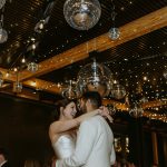 Newlywed couple dancing under disco balls and string lights at elegant wedding reception