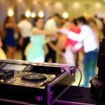 DJ equipment with wedding guests dancing in blurred background