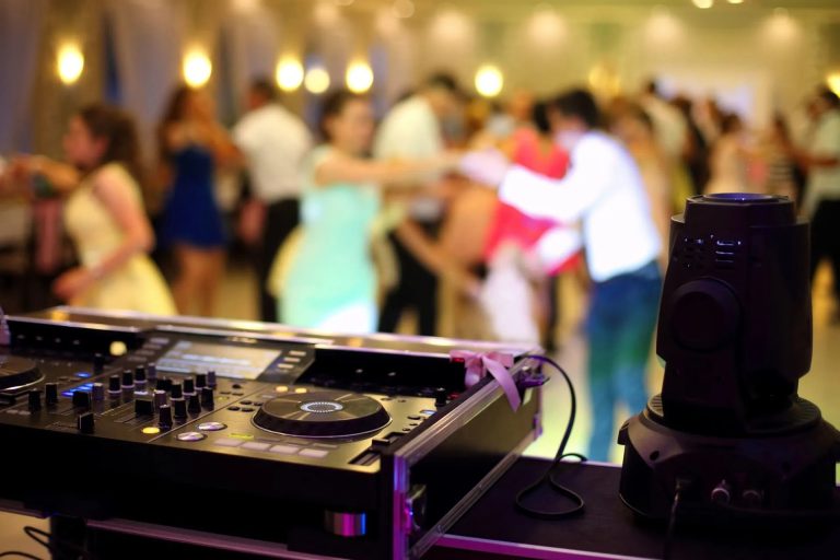 DJ equipment with wedding guests dancing in blurred background