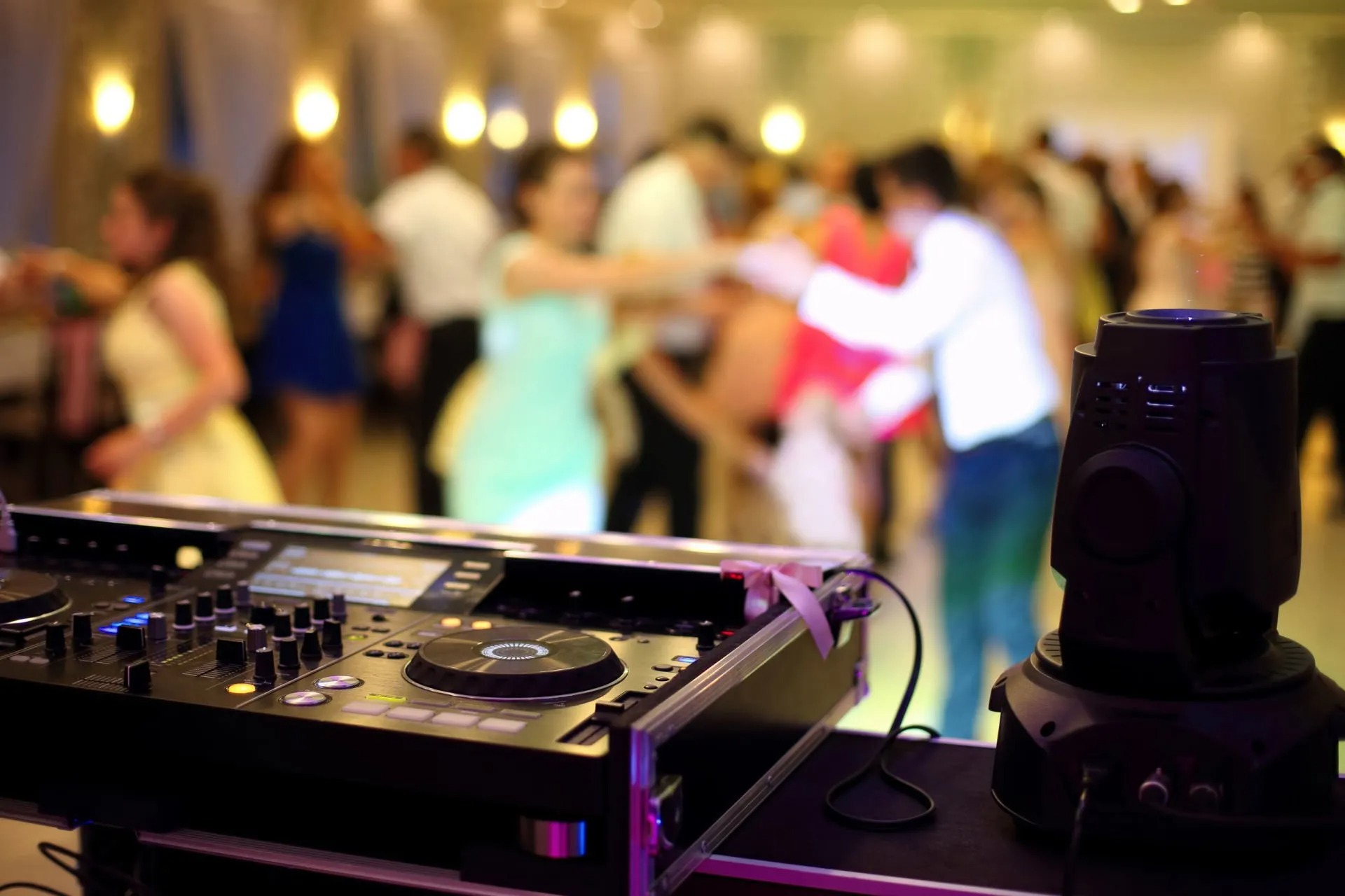 DJ equipment with wedding guests dancing in blurred background