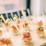 Elegant spoon appetizers with diced tomato mixture arranged on wooden platter for wedding reception