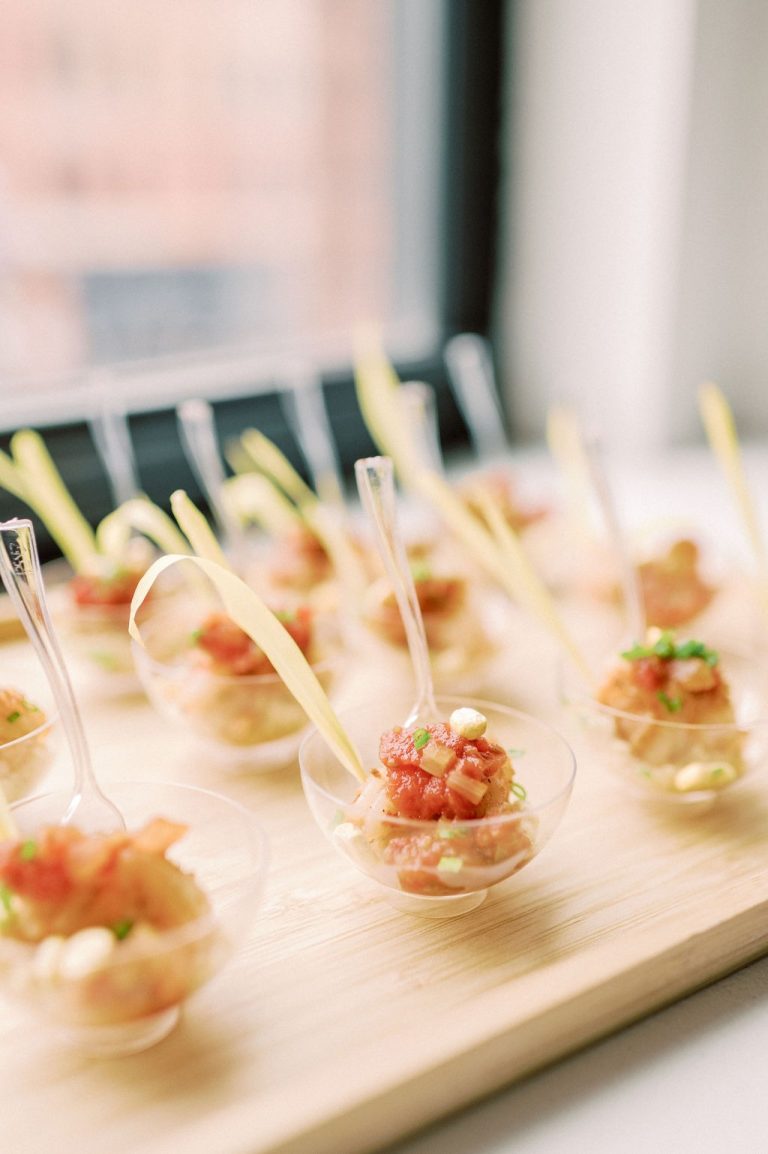 Elegant spoon appetizers with diced tomato mixture arranged on wooden platter for wedding reception