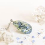 Teardrop pendant necklace containing preserved blue wedding flowers in clear resin
