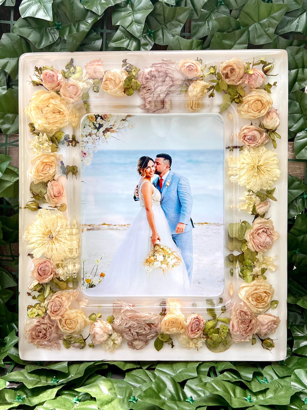 White resin picture frame decorated with preserved wedding flowers in cream, peach, and coral tones