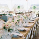 Outdoor wedding reception with mix of round and long tables featuring blue linens and white floral arrangements