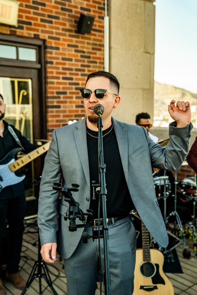 Male vocalist in gray suit and sunglasses performs with live band at outdoor wedding reception