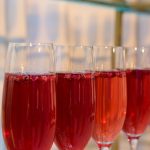 Champagne flutes filled with red sparkling cocktails ready for service