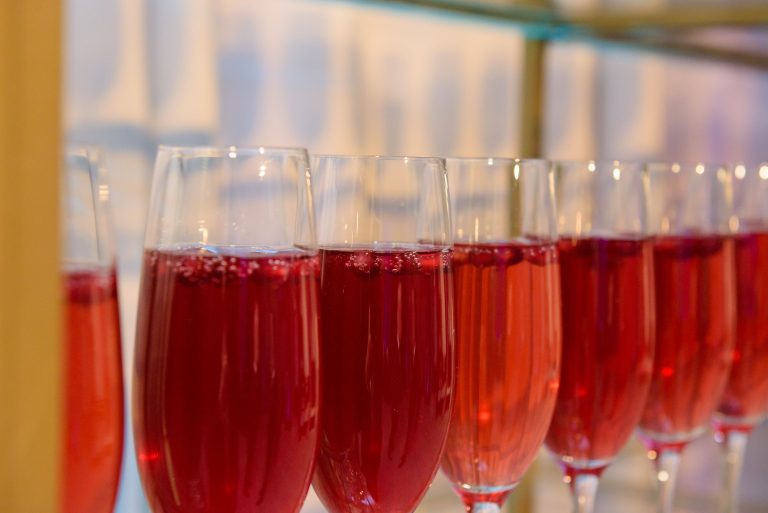 Champagne flutes filled with red sparkling cocktails ready for service