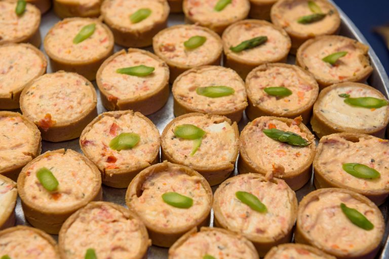 Savory mini quiches topped with jalapeño slices on catering tray