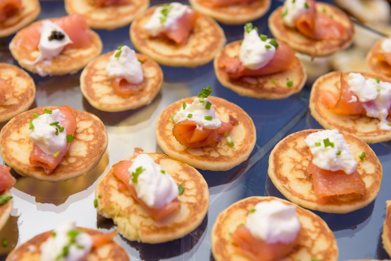 Mini blini topped with smoked salmon, crème fraîche, and fresh chives