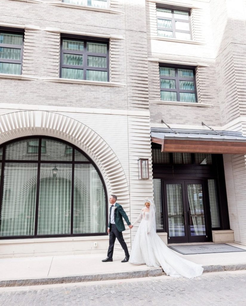 Anna and Griffin walking hand-in-hand outside Perry Lane Hotel's modern architectural entrance