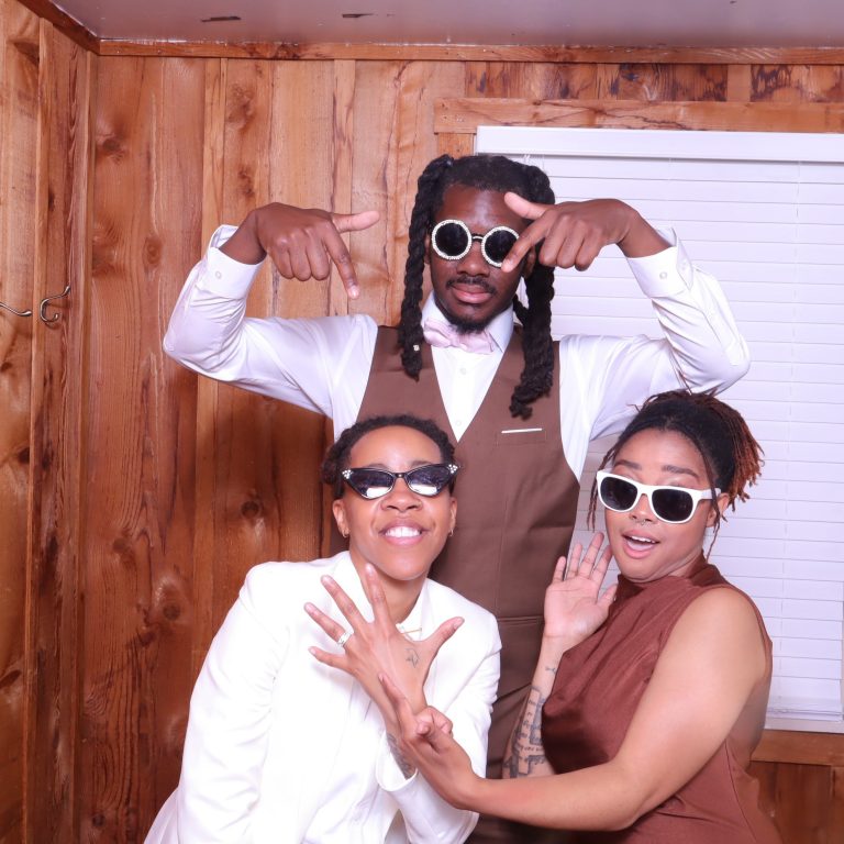 Wedding guests in formal attire wearing novelty sunglasses and striking playful poses