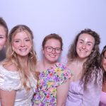 Bridesmaids in white dresses holding colorful bouquets in a photo booth