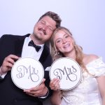 Newlywed couple holding "Mr" and "Mrs" signs at their wedding photo booth