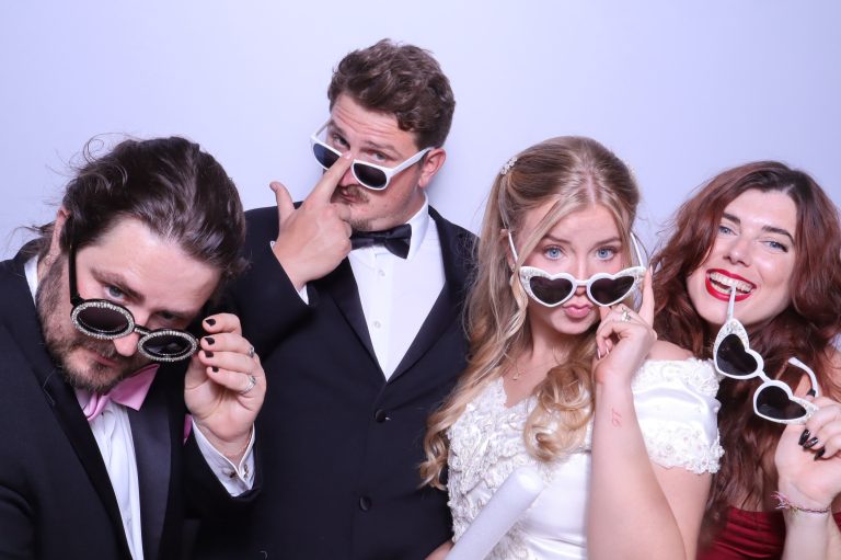 Wedding party in formal attire posing with oversized novelty sunglasses props