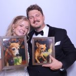 Bride and groom in formal attire holding photo booth props in decorative frames