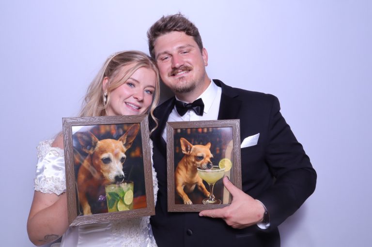 Bride and groom in formal attire holding photo booth props in decorative frames