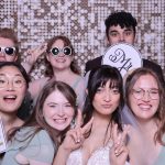 Group of wedding guests posing together with props against sequin backdrop