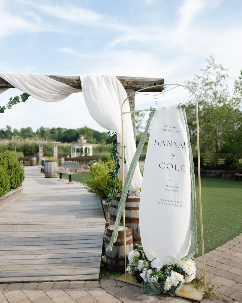 The Elliot's Rosehip Room bar area with gold-fronted counter, white bar stools, floral garland, and exposed wooden beam ceiling