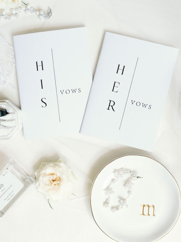Minimalist wedding vow books reading "His Vows" and "Her Vows" with monogrammed jewelry dish and flowers