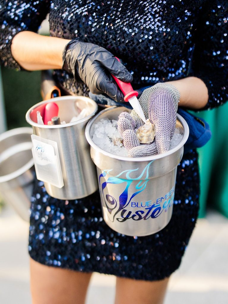 Guest in sequined dress holds rhinestone-covered champagne buckets filled with ice at the reception