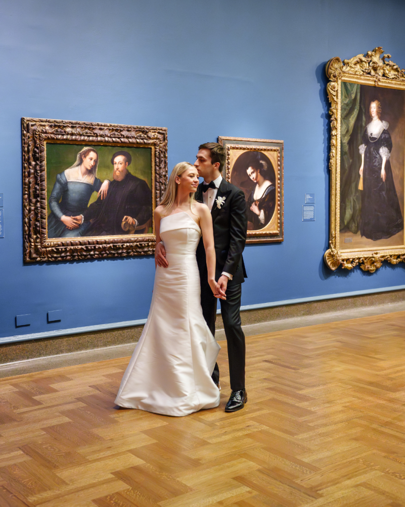 Bride and groom share intimate moment in art museum gallery with blue walls and ornate portrait paintings