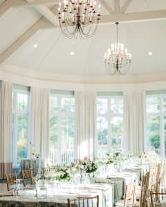 Airy reception hall with white decor, natural lighting, and greenery-accented table arrangements