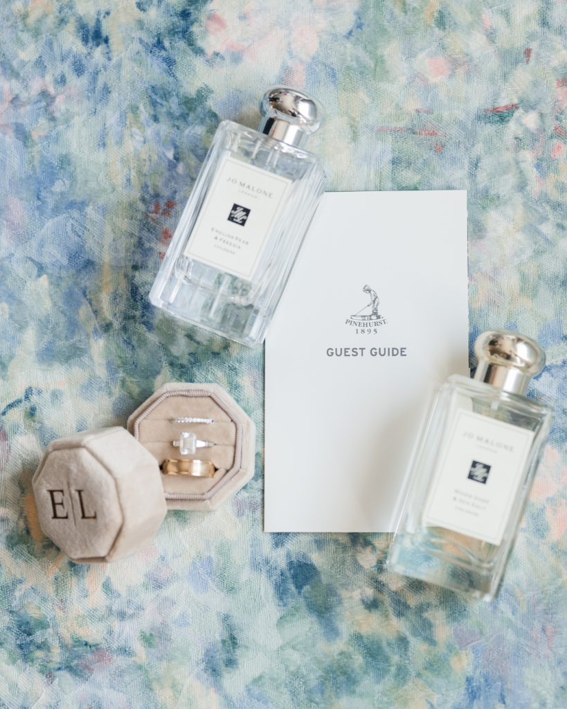 Wedding rings in monogrammed velvet box displayed with Jo Malone perfume bottles and Pinehurst guest guide