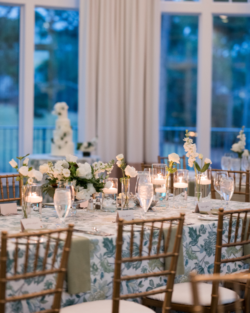 Elegant reception table with white florals, floating candles, and botanical linens at twilight