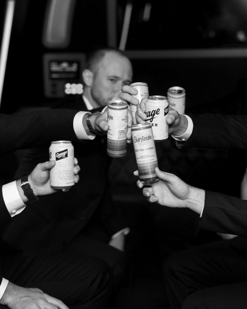 Groom and groomsmen toast with canned beverages in black and white