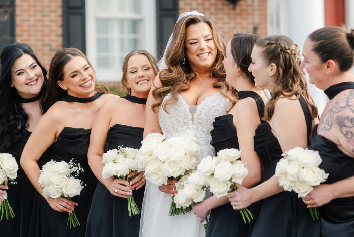 Bride with bridesmaids in black dresses holding white bouquets at King Cole Farm wedding in Dover Delaware