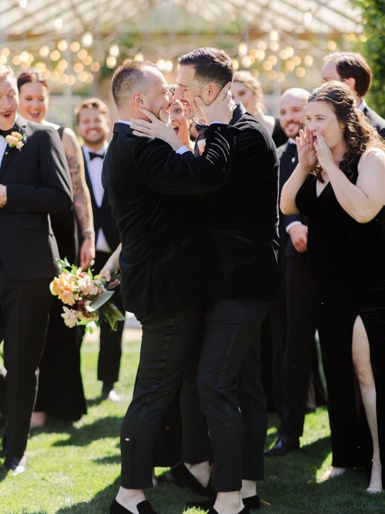 Stephen and Austin share their first kiss as married couple while wedding guests cheer and applaud outdoors at Jorgensen Farms