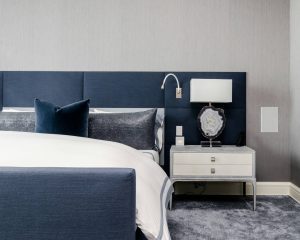 Close-up of hotel bed with navy headboard and modern white nightstand