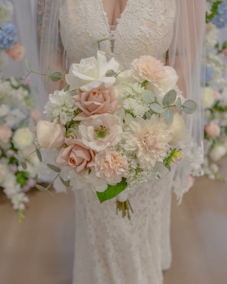 Soft pink and white bridal bouquet featuring roses, dahlias, ranunculus, and eucalyptus greenery