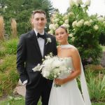 Wedding couple in tuxedo and bridal gown posing together outdoors