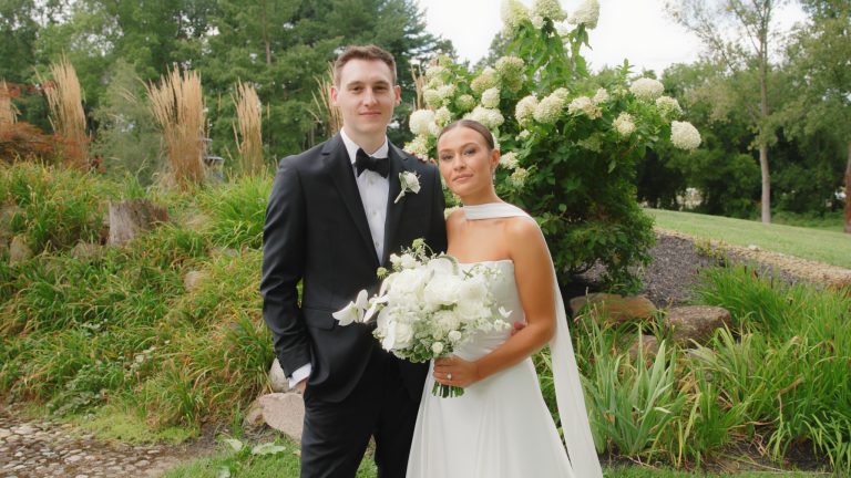 Wedding couple in tuxedo and bridal gown posing together outdoors
