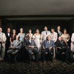 Formal wedding family portrait with bride, groom, and extended family members in elegant lighting