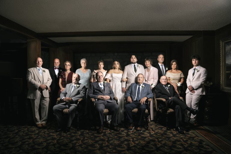 Formal wedding family portrait with bride, groom, and extended family members in elegant lighting